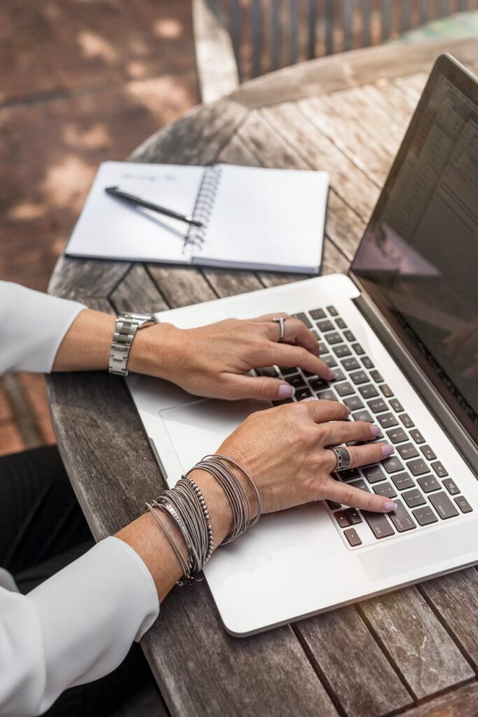 A woman's hands typing on a laptop